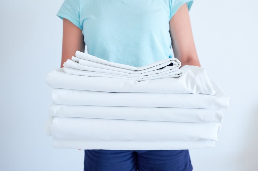 femme tenant une pile de linge de maison plié